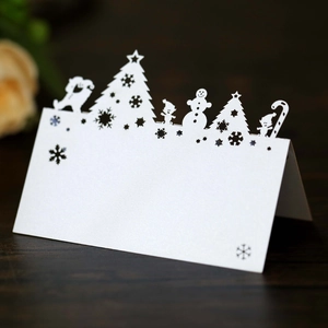 Detailed laser-cut Christmas reindeer and snowflake place card on dark wood surface