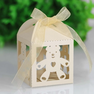 Detailed laser-cut teddy bear patterns on a cream paper candy box with a ribbon bow