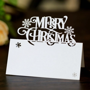 Macro shot of white laser-cut Merry Christmas table cards with snowflake hollow details
