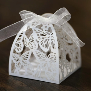 Detailed macro view of laser-cut butterfly wedding favor box with white organza ribbon bow