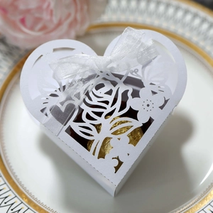 Détail de la boîte à bonbons coeur ajourée blanche avec motif rose et ruban