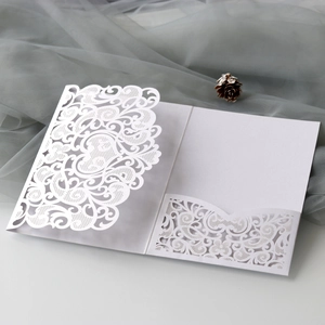 Macro view of white laser-cut floral invitation cover with hollow engraved pocket sleeve