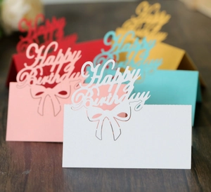 Close-up of laser-cut Happy Birthday table name cards in colorful hollow cardstock
