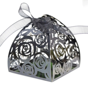 Detail of laser-cut black favor box with rose patterns and organza ribbon bow