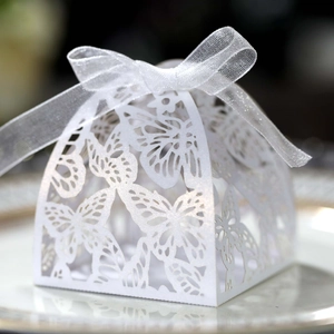 Close-up of laser-cut butterfly gift box with white organza ribbon on a gold-rimmed plate