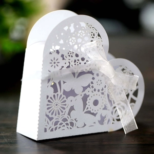 Macro shot of white laser-cut butterfly heart favor box with elegant organza ribbon