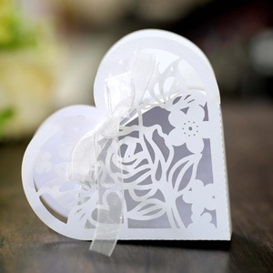 Gros plan sur une boîte à dragées en cœur blanche avec roses découpées au laser et ruban