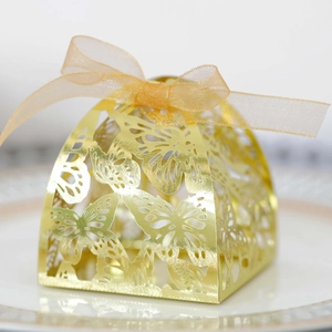 Detail of laser-cut butterfly hollow wedding candy box with gold organza ribbon bow