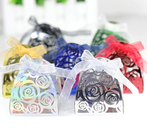 Close-up of laser-cut rose hollow favor boxes with iridescent metallic finish and ribbons