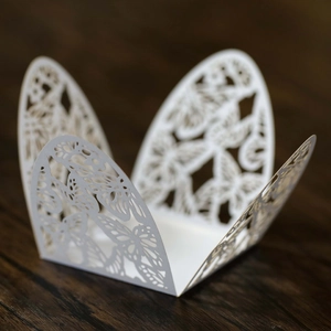 Macro shot of white laser-cut butterfly hollow candy box on dark wood background