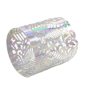 Detailed view of laser-cut vine patterns on iridescent silver metal napkin ring