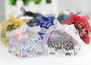 Detail of laser-cut rose patterns on silver candy boxes with organza ribbons