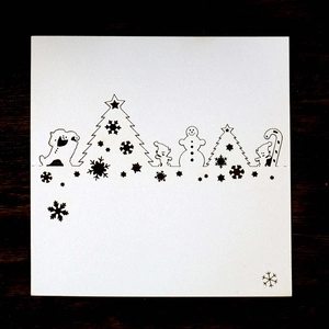 Laser-cut Christmas tree and snowman silhouette on a dark green table place card