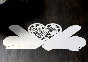 Vue à plat d'une boîte de mariage en papier perlé blanc découpé au laser avec cœur rose
