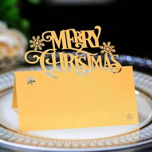 Close-up of golden laser-cut Merry Christmas place card with snowflake on dining plate