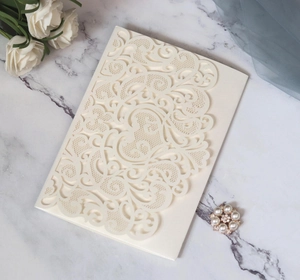 Detail of cream laser-cut wedding invitation with elegant floral hollow pattern