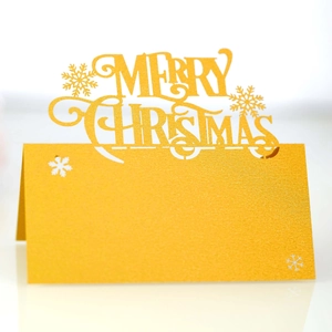 Close-up of laser-cut gold glitter Merry Christmas place cards with snowflake details