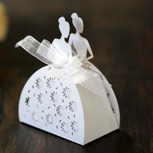 Macro shot of laser-cut wedding favor box with ribbon and elegant silhouettes
