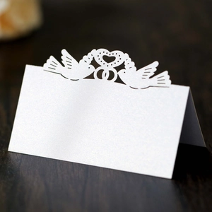 Laser-cut white pearlescent place card featuring lovebirds and heart design for weddings
