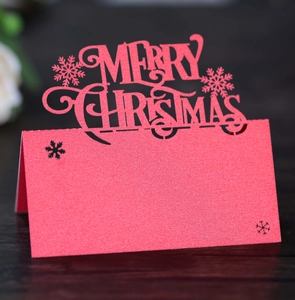Macro shot of red laser-cut Merry Christmas seat card with snowflakes on wood