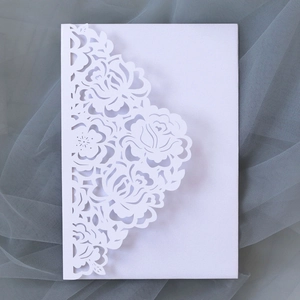 Detailed close-up of white laser-cut floral invitations with elegant lace rose patterns