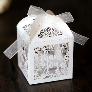 Macro detail of laser-cut white favor box with thank you text and organza ribbon