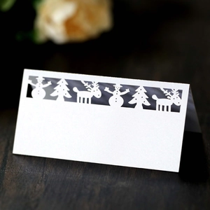 Macro view of white pearlescent paper table cards with laser-cut Christmas reindeer patterns