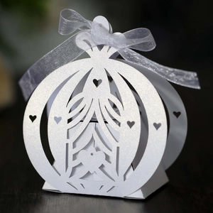 Macro detail of laser-cut pumpkin carriage gift box with heart hollows and white ribbon