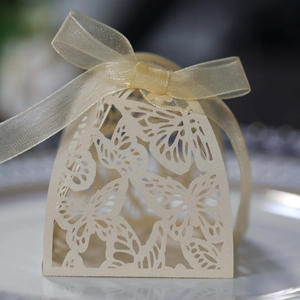 Detailed laser-cut butterfly hollow pattern on cream-colored wedding favor box with ribbon