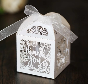 Detail of white laser-cut gift box with floral thank you pattern and organza ribbon