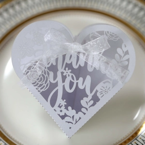 Macro view of laser-cut heart favor box with Thank You text and white ribbon detail