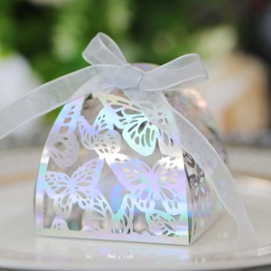 Detail of laser-cut iridescent butterfly favor box with elegant white organza ribbon bow
