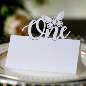 Macro detail of white laser-cut butterfly place card with 'One' text for birthday parties