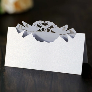 Macro detail of laser-cut white wedding place cards with heart and bird motifs