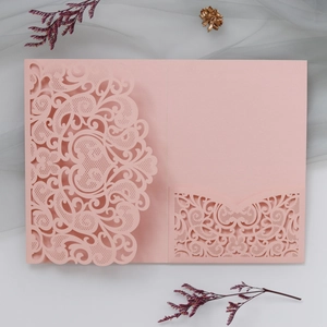 Detail of laser-cut pink wedding invitation cover with elegant floral lace patterns