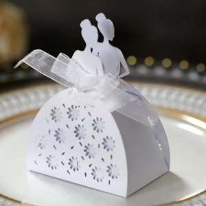 Close-up of laser-cut wedding favor box with elegant female silhouettes and white ribbon