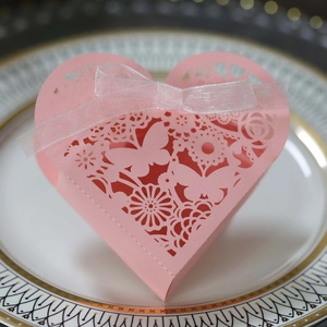Pink heart-shaped laser-cut gift box featuring intricate floral lace and white ribbon
