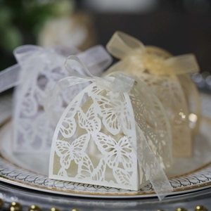 Macro detail of laser-cut butterfly wedding favor boxes with elegant silk ribbons