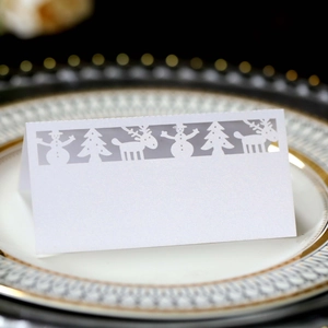 Detail of laser-cut white Christmas place card with reindeer on gold-rimmed plate