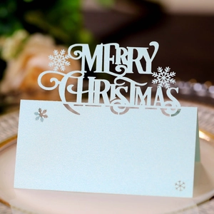 Macro shot of light blue pearlescent laser-cut Merry Christmas snowflake table place card