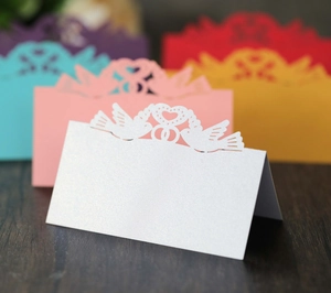 Close-up of laser-cut place card with bird heart pattern in premium pearlescent paper