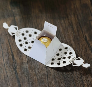 Detail of laser-cut white candy box featuring an elegant bride silhouette and floral patterns