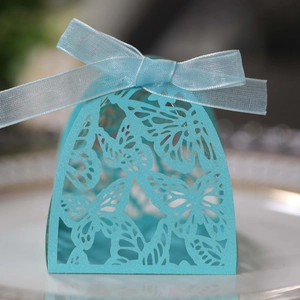 Macro shot of laser-cut butterfly gift box with elegant blue ribbon on a porcelain plate