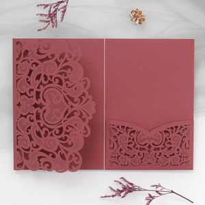Macro view of burgundy laser-cut wedding invitation with intricate floral vine patterns