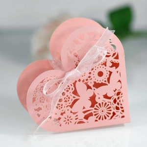 Macro shot of pink laser-cut heart favor box with butterfly patterns and ribbon bow