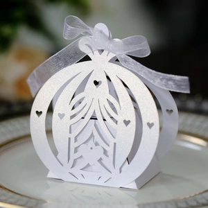 Detail of white laser-cut pumpkin carriage wedding favor box with pearl finish ribbon