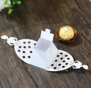 Detail of white laser-cut bridal dress favor box with floral patterns on wooden table