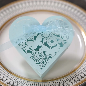 Detail of laser-cut heart favor box with butterfly patterns and blue organza ribbon