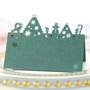 Macro detail of dark green laser-cut Christmas table card with festive snowflake patterns