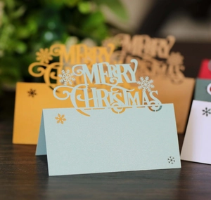 Laser-cut Merry Christmas table cards in light blue and yellow cardstock with snowflake detail